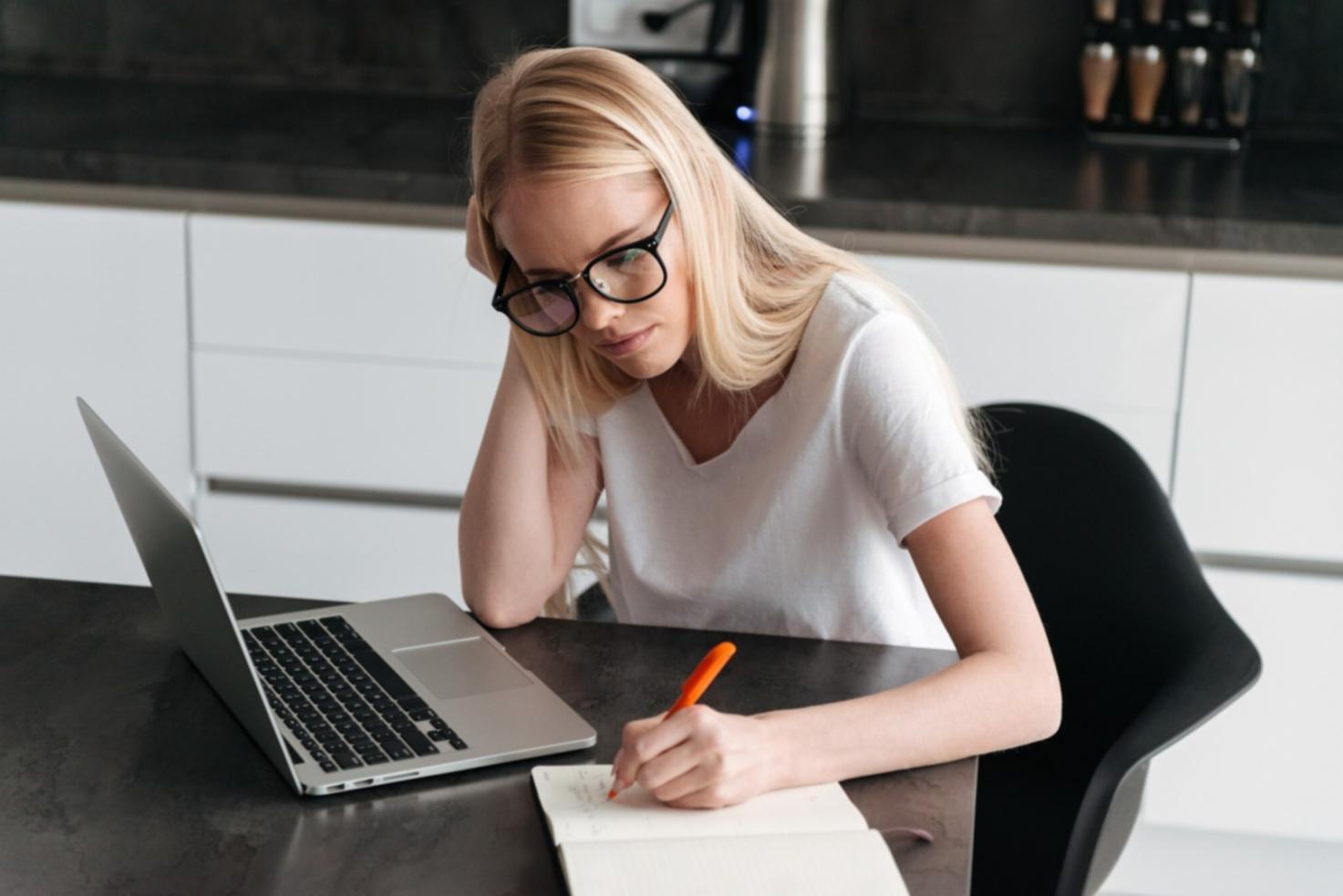 Person studying financial materials on laptop in comfortable home setting